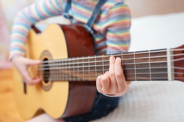 어린 소녀는 집에서 기타를 재생합니다.