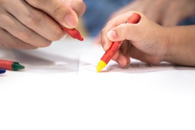 Little girl plays and learns to coloring Crayon on the paper in the ice-cream restaurant., Bangkok, Thailand.