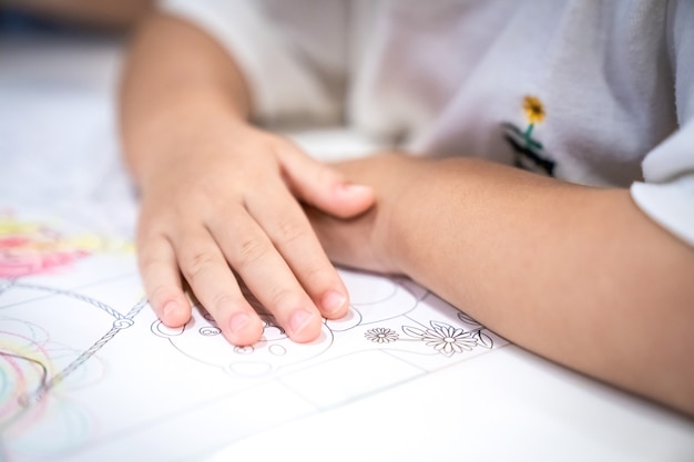 Little girl plays and learns to coloring Crayon on the paper in the ice-cream restaurant., Bangkok, Thailand.