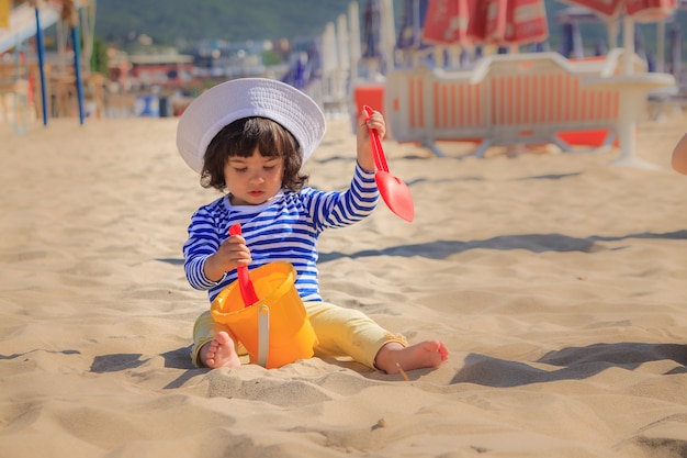 小さな女の子はビーチで砂で遊ぶ