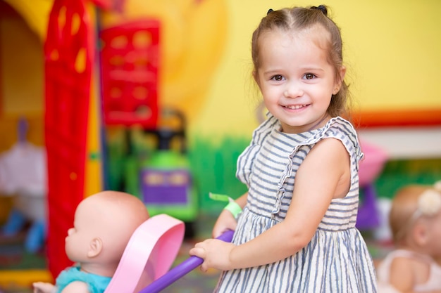 Little girl plays with a doll and smiles