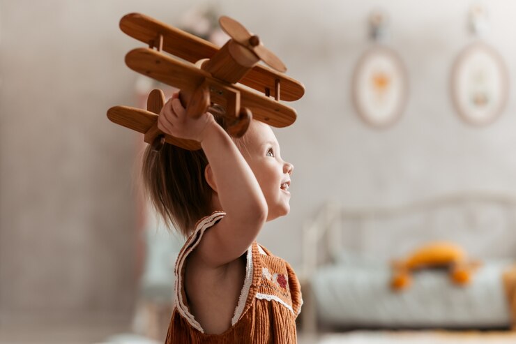 小さな女の子はおもちゃの木の飛行機で遊ぶ