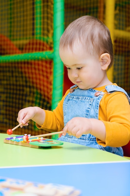 A little girl plays with a xylophone in the playroom