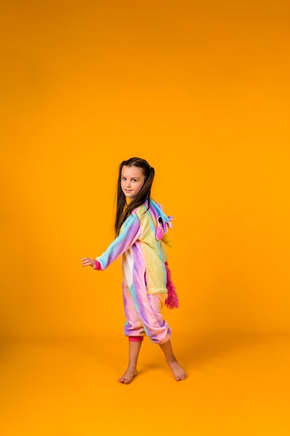 A little girl in a plush costume dances on a yellow background with a place for text