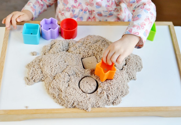 Little girl plyaying with kinetic sand at home