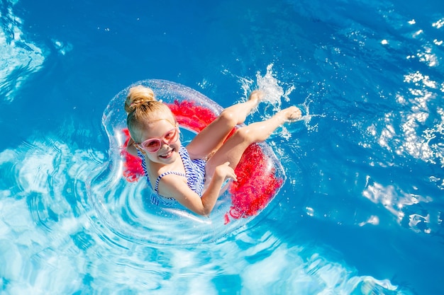 Little girl plying in the pool on a mattress