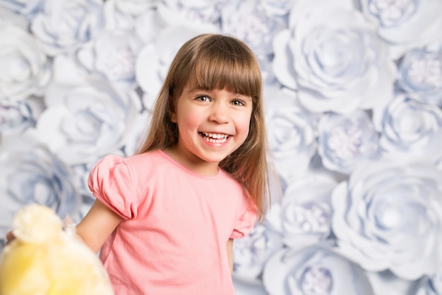 Foto ritratto della bambina su una priorità bassa del fiore di carta