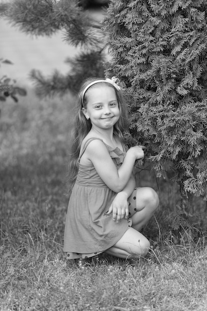 Little girl pose at green bush on grass beauty