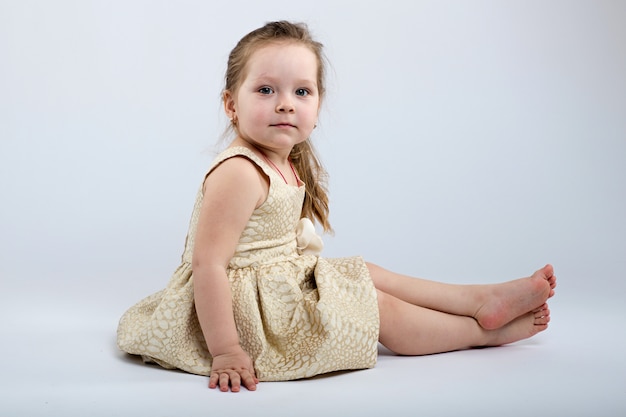 Little girl poses in beautiful dress on grey background