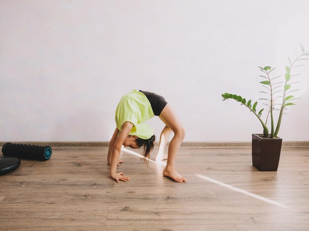 Little girl posing while standing in bridge pose at home Stretching in yoga Beauty and health at home