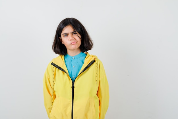 Little girl posing while standing in shirt, jacket and looking thoughtful , front view.