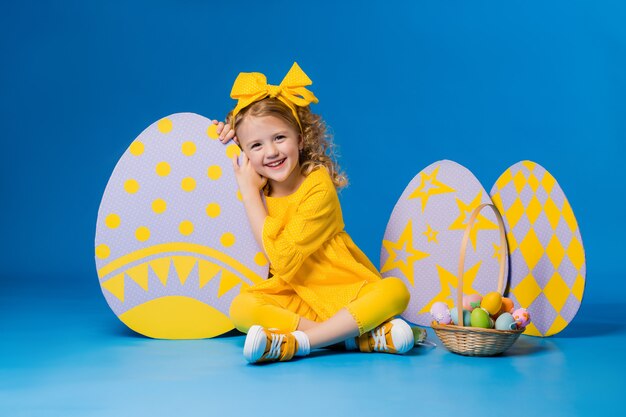 Little girl posing with a row of large decorative Easter eggs