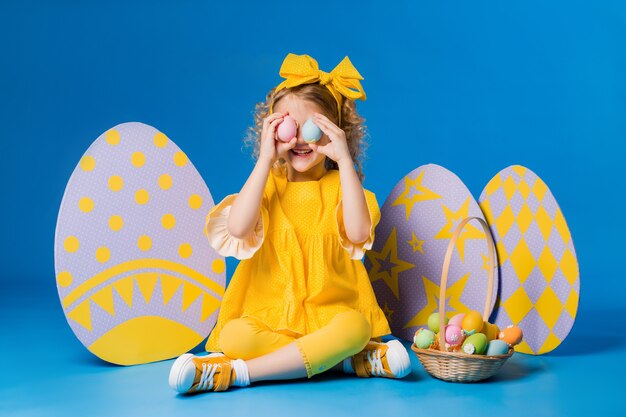 Little girl posing with a row of large decorative Easter eggs