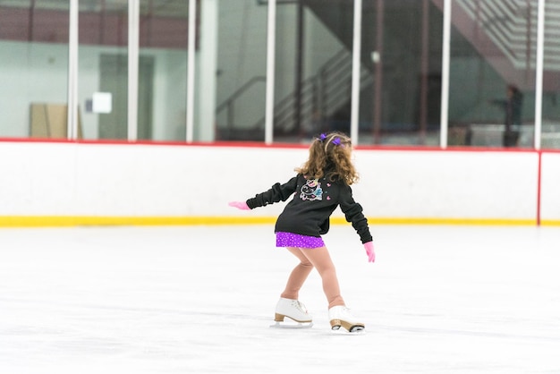 Little girl practicing figure skating on an indoor ice skating rink