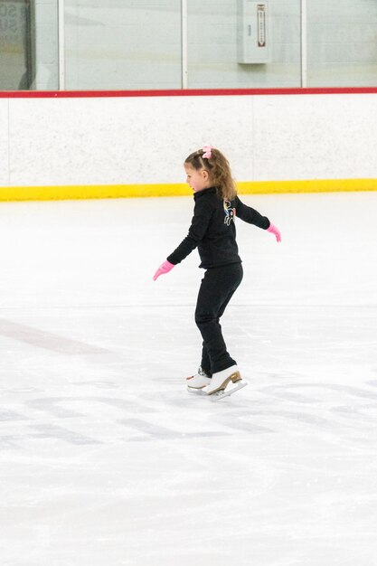 Little girl practicing figure skating moves on the indoor ice rink.