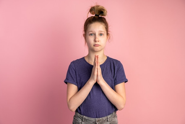 Little girl praying on pink wall