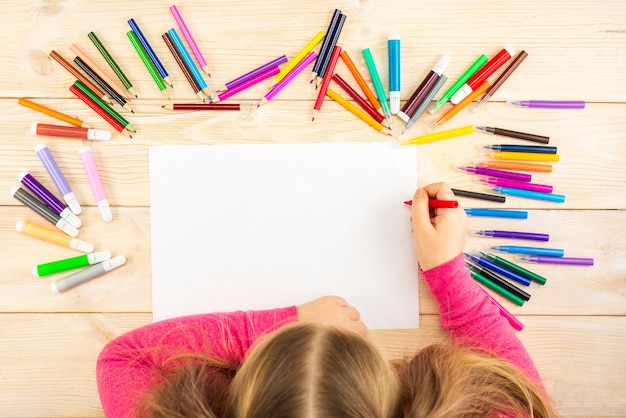 La bambina si prepara a dipingere su un foglio di carta bianco.