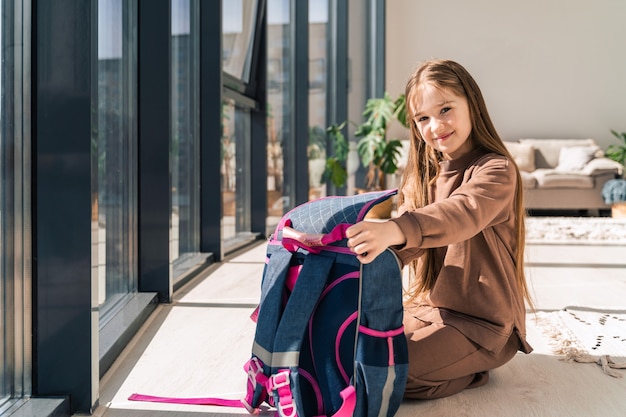 Little girl prepares school backpack