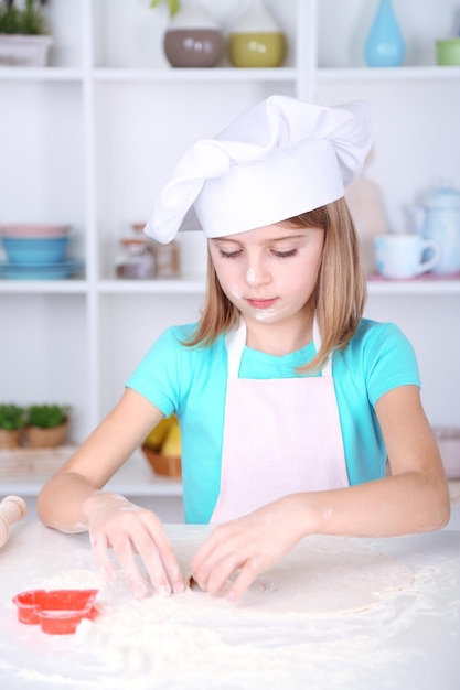 Little girl preparing cookies in kitchen at home