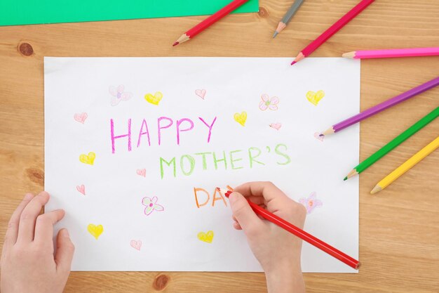 Little girl preparing greeting card for her mommy on Mother's Day at table