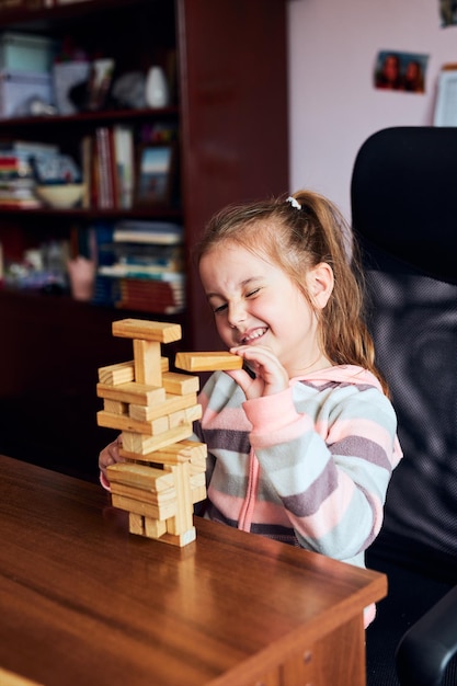 Piccola bambina in età prescolare che gioca con blocchi di legno giocattolo costruzione di una torre concetto di costruzione di una casa