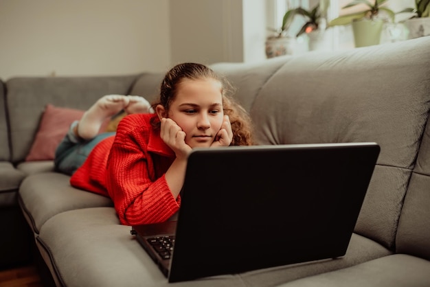 Little girl a preschooler uses a laptop to study at home the\
child smiles happily and receives knowledge remotely digital\
concept of elearning distance elearning