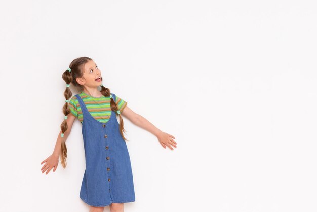 A little girl pressed against the wall looks sideways at your advertisement on a white isolated background Copy space