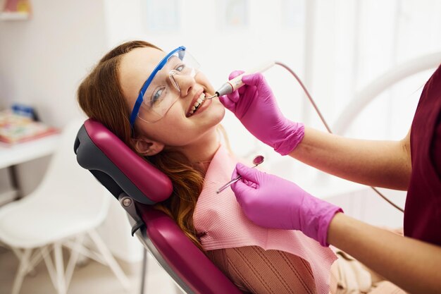 Little girl in protective glasses visiting dentist in clinic Conception of stomatology