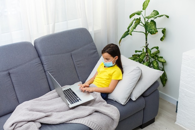 little girl in a protective mask at distance home schooling, quarantine