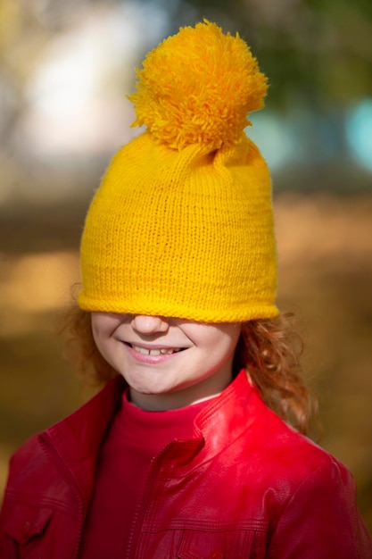 Photo the little girl pulled a yellow knitted hat over her eyes fall has come