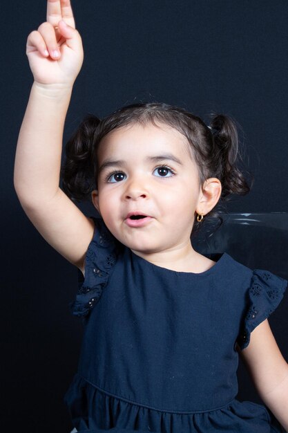 Маленькая девочка поднимает палец, чтобы заговорить