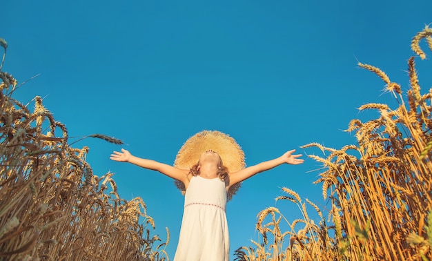 Little girl raising her hands to the sky in a wheat field