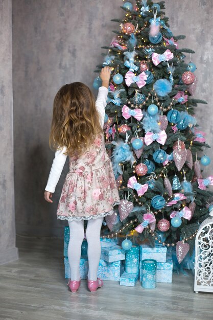 Premium Photo | A little girl reaches for a christmas tree toy ...