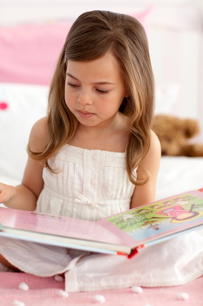 Little girl reading in bed