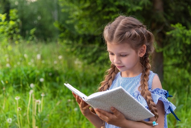 little girl reading a book in the forest