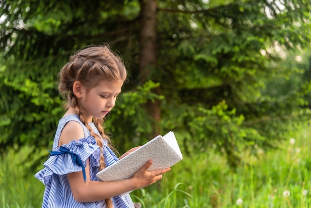 Bambina che legge un libro all'aperto