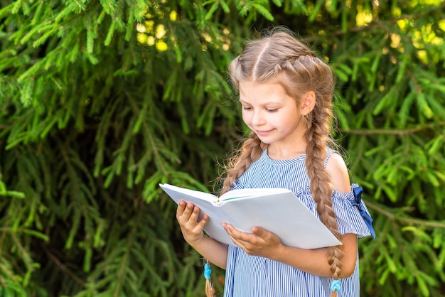 Little girl reading a book in the woods.