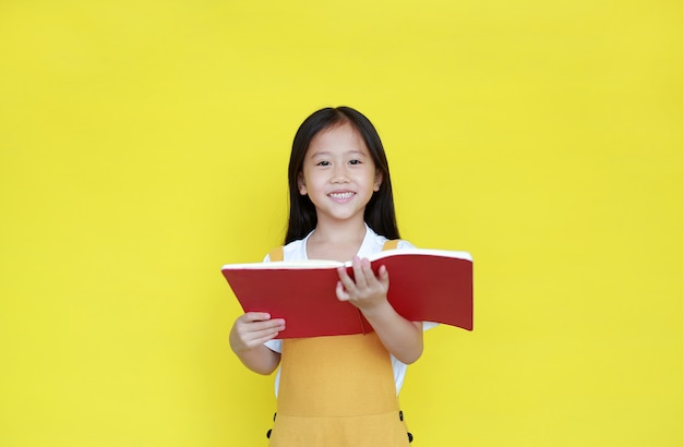 Little girl reading book on yellow background