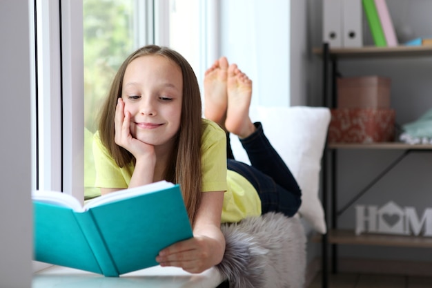 Little girl reads a book at home