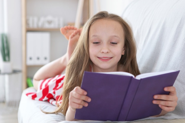 Little girl reads a book at home