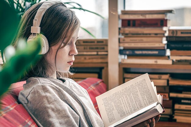 A little girl reads a book and listens to music on headphones