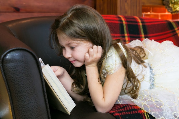 Little girl reads a book with interest.