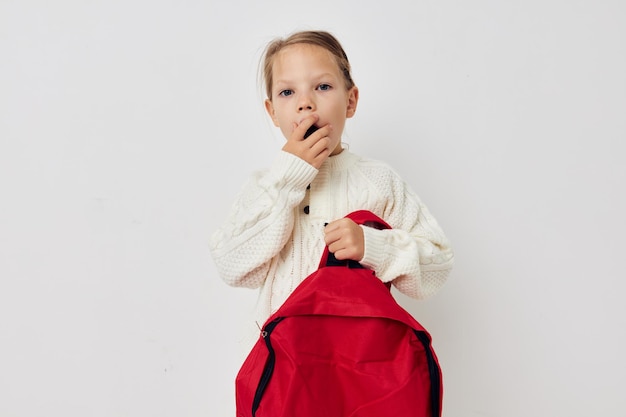 Маленькая девочка красный рюкзак стильная одежда изолированный фон
