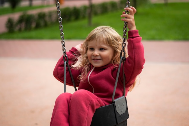 little girl in red clothes swinging on a swing