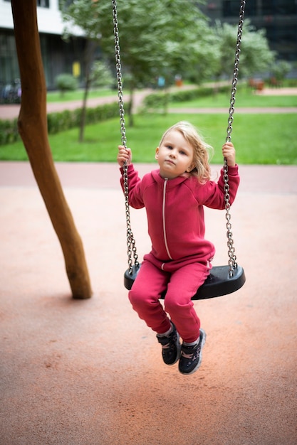 little girl in red clothes swinging on a swing