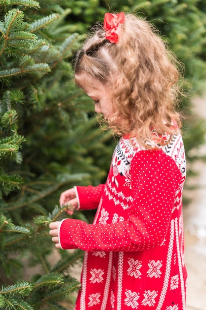 Bambina in vestito rosso alla fattoria dell'albero di natale