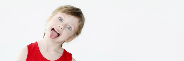 Photo little girl in red dress showing tongue. happy childhood concept