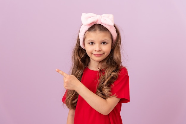 A little girl in a red T-shirt points her finger at the advertisement.