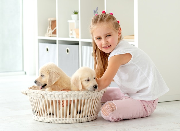 Little girl and retriever puppies