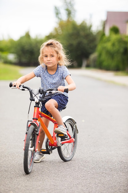 The little girl rides a bike in the city